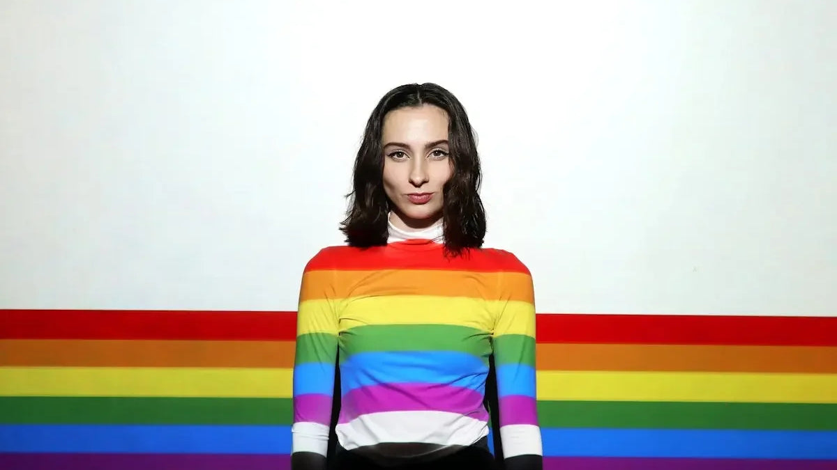 a woman standing in front of a rainbow colored wall