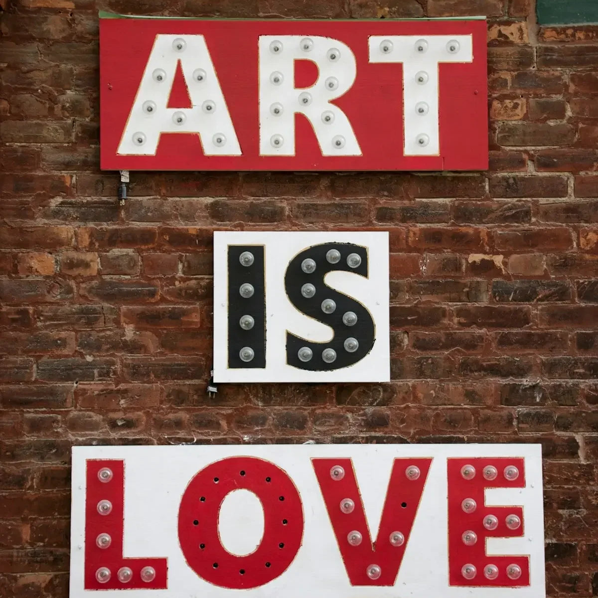 a sign that says art is love on a brick wall